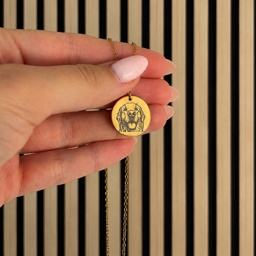 Gold pet portrait pendant held in hand — engraving detail