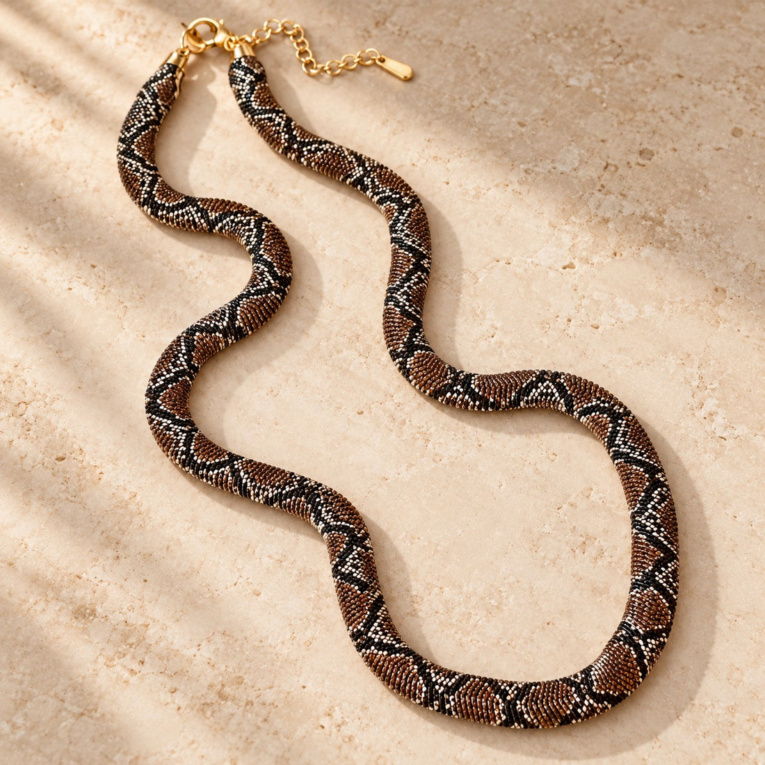 Braided snake necklace laid flat on stone